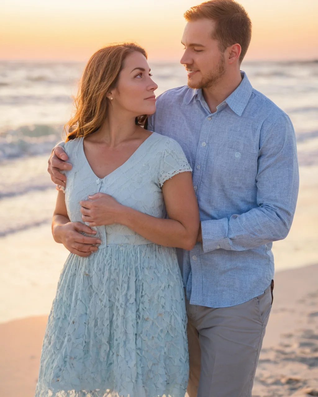 A couple hugging on a beach during sunset with ocean in background